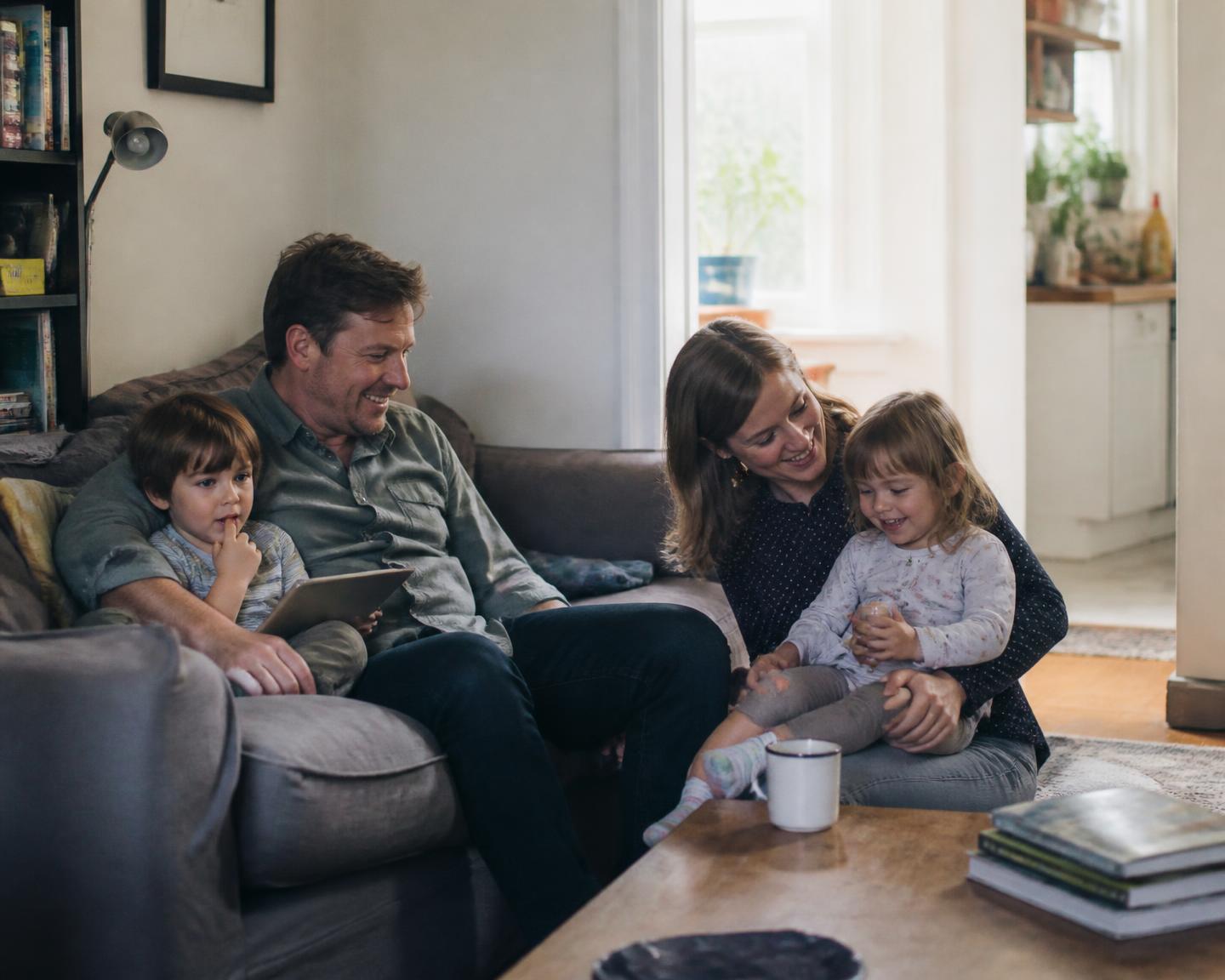 A family sitting together on the sofa in the living room of their home